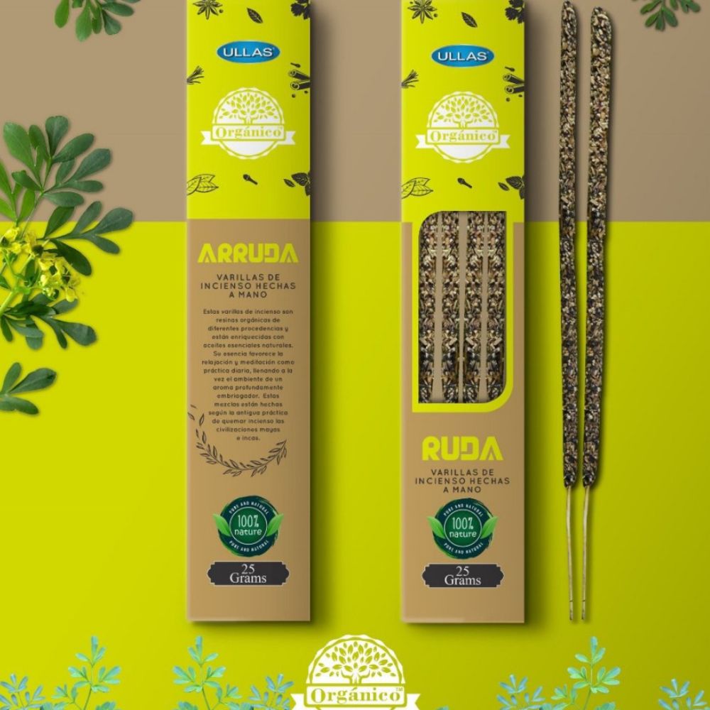 Two boxes of organic Arruda and Ruda incense sticks displayed on a yellow-green surface, with three natural incense sticks partially out of one box. Boxes have rectangular cardboard packaging with a matte finish and printed labels reading “Arruda” and “Ruda” in bold, clear type. Decorative green leaves are placed in the background. No people or hands are visible; the shot is top-down.