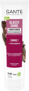 Sante Glossy Shine Hoitoaine; tuubi koivulla ja provitamiini B5:llä rikastettua hoitoainetta, merkitty mattahiuksille; vegaaninen pakkaus sisältää ekosertifiointeja ja tekstiä sekä saksaksi että englanniksi; pakkaus on valkoinen muovituubi mattapinnalla, vihrein korostein ja mustalla groteskikirjasimella; kuvattu pystyssä vaalealla taustalla tasaisessa valaistuksessa, ei ihmisiä tai käsiä näkyvissä.