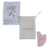 SkinMood Gua Sha Beauty Tool Hierontalasta; SKINMOOD-gua sha -työkalu sileän vaalean kivimäisen pinnan ja kaarevan muodon kera, vieressä kermanvärinen kangaspussi narusuljennalla; ohjelehti näyttää mustan kasvokaavion ja painettua tekstiä; kaikki aseteltu valkoiselle taustalle, ei ihmisiä tai käsiä kuvassa.