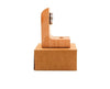 A wooden L-shaped object with a metal component on its inner corner sits on top of a closed brown cardboard box, both set against a plain white background. The wood has a matte finish and the object is angular. The metal piece is silver in color and contrasts with the wood. No labels or text are visible. No people or hands are present in the image. This is a straightforward product shot.