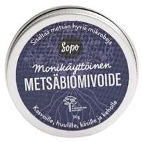Sopo Mustikkainen Metsäbiomi; pyöreä metallinen tölkki mattapinnalla, etiketissä teksti "Sopo Monikäyttöinen Metsäbiomivoide" tarkoitettu kasvoille, huulille, käsille ja vartalolle, sisältää hyödyllisiä metsämikrobeja; koostumus valmistettu ravitsevilla metsämikrobeilla monikäyttöiseen hoitoon; etiketti yksinkertaisella groteskitekstillä mustana vaaleaa pohjaa vasten; ei ihmisiä eikä käsiä näkyvissä, tuote kuvattu tasaisella pinnalla tasaisessa valaistuksessa.
