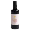 A dark spray bottle with a pink and white label featuring gold and pink circles, subtle line art, and elegant design details. The bottle has a cylindrical shape with a smooth finish. The label includes some text that is not clearly readable, using light contrasting colors for certain elements. The background is plain white. The image shows only the product without people or hands.