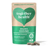 A green and beige, matte-finish pouch labeled “together health Organic Iodine from wild seaweed” sits upright, accompanied by two light-colored vegan capsules positioned in front. Notable sans-serif fonts and minimalistic label design are visible. The package highlights natural ingredients and contains 30 capsules. Plain background; no people or hands are present in the shot.