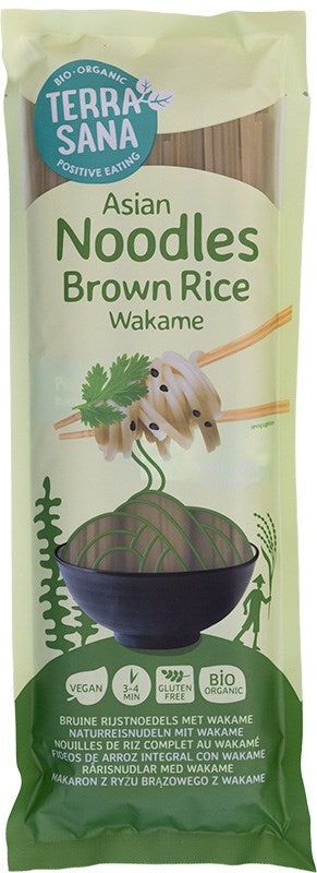 Package of TerraSana Asian Brown Rice Wakame Noodles, featuring a bowl of gluten-free noodles with chopsticks, green graphics, and labels for vegan and organic. Rectangular plastic packaging with matte finish. Front displays product name in bold white font; smaller sans-serif text shows “vegan” and “organic”. Image of prepared noodles on white plate. No people or hands present. Plain light background. Studio shot.