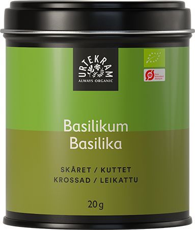 Urtekram Luomu Basilika, vihreä tölkki luomubasilikalle merkittynä usealla kielellä, mustalla kannella, sisältää 20 grammaa tuoksuvaa yrttiä; metalliastia sylinterimäinen ja mattapintainen, yksinkertainen painettu teksti etusivulla groteskifontein; tölkki seisoo pystyssä valkoista taustaa vasten, ei muita esineitä eikä ihmisiä kuvassa.