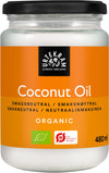 A jar of Urtekram Organic Coconut Oil with an orange label, displaying its 480 ml size, flavor-neutral profile, and organic certification logos. The jar is cylindrical, transparent glass with a metallic screw-on lid. The label has sans-serif white text on an orange background and includes certification symbols. Neutral background; no people or hands visible; studio product shot.