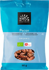 A blue 50g Urtekram bag labeled “Pecan.” The front shows images of whole pecan nuts, organic certification symbols, and product weight. Text uses a mix of sans-serif fonts in varying sizes. Packaging is matte, flexible plastic with a heat-sealed top. Background is plain and well lit. No people or hands are present in the image. A blue 50g Urtekram bag labeled Pecan, featuring pecan nuts and organic certification symbols on the front, highlights its organic quality.