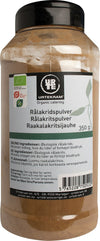 A jar of Urtekram organic catering licorice powder with multilingual labeling, ingredients, and nutritional advice on the front. The cylindrical plastic jar has a black matte screw-top lid. Label includes block sans-serif text and a barcode in the bottom right corner. The packaging indicates organic certification marks. Plain, neutral background with no people or hands visible in the image.