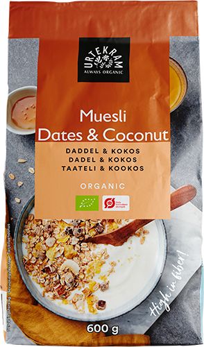 A 600g bag of Urtekram organic muesli with dates and coconut. The packaging is matte, primarily in light teal with white and brown accents. There is an image of a ceramic bowl containing muesli and milk on the front. Notable text includes product name, flavor details, weight, and “high fiber.” Sans-serif fonts are used. No people or hands present. Plain background; product shown upright in a studio shot.