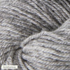 A close-up view of light gray yarn, showing its soft texture and twisted fibers. The yarn is matte and fibrous with a loose twist visible in the strands. In the lower left corner, there is a small label with the text keskiharmaa in simple, clear typography. There is no visible packaging apart from the label. No people or hands are present in the image.