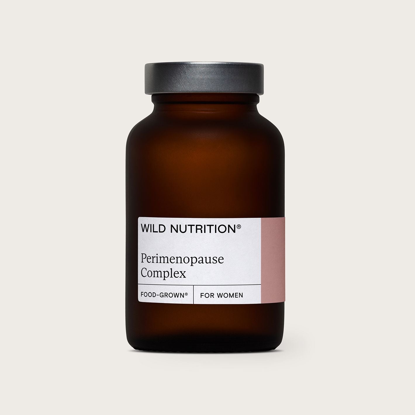 A brown glass bottle labeled Wild Nutrition Perimenopause Complex, featuring the text Food-Grown and For Women on a white and pink label, stands against a plain light background. The cylindrical bottle has a silver screw cap and a matte surface. The main text uses sans-serif font in black, with some smaller red elements. There are no people or other objects visible, captured in a centered product shot.