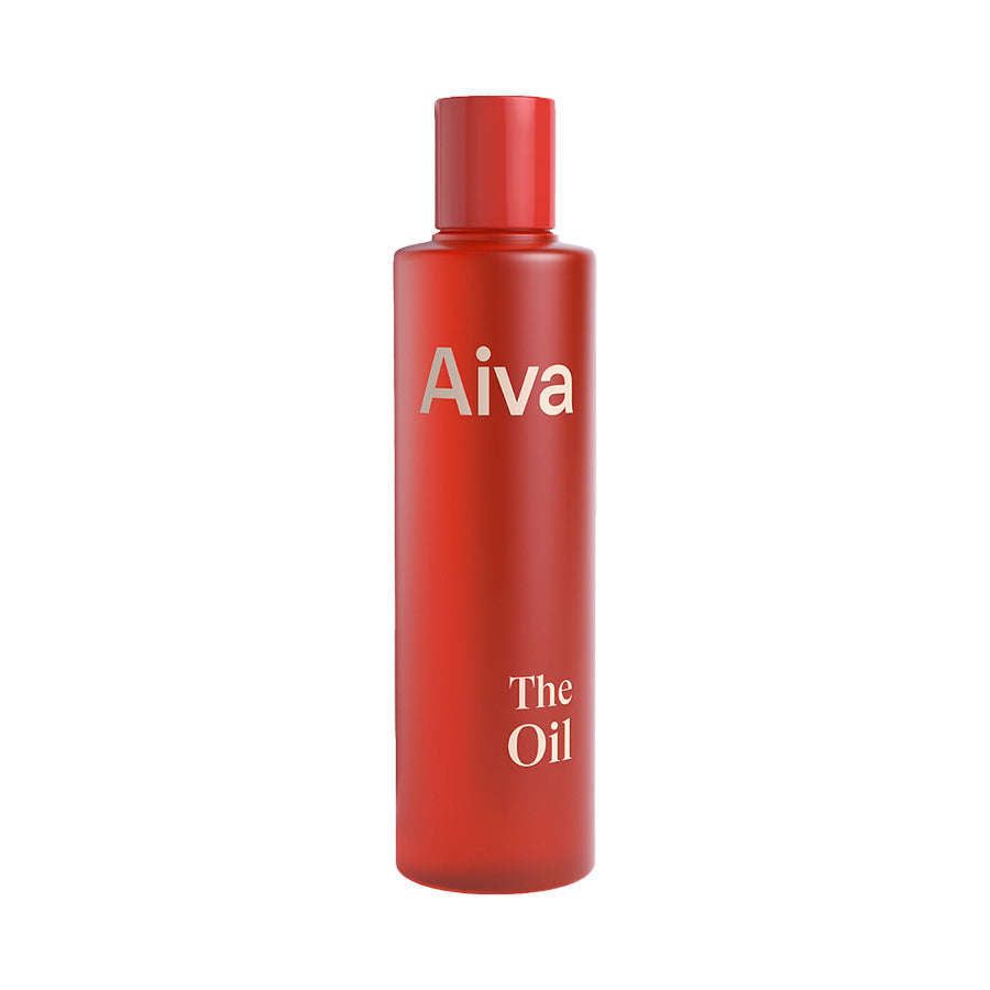Aiva The Oil; punainen pullo tekstillä "Aiva The Oil" pystyssä valkoisella taustalla; astia muovia tai lasia sylinterinmuotoisena painetulla tuoteetiketillä; ei ihmisiä tai käsiä kuvassa, ympäristö pelkistetty ja tasaisesti valaistu.