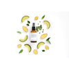 Evolve True Balance Tasapainottava Kasvovoide; ruskea suihkepullo muovisella liipaisimella, puolimatta pinta, ei näkyvää etikettiä tai brändimerkintää, lieriömäinen muoto; ympärillä siististi aseteltuja avokadoviipaleita, inkiväärinpaloja kuorineen ja hedelmälihoineen, litteitä vihreitä lehtiä ja pieniä vihreitä yrttioksia; kaikki aseteltu vaalealle taustalle ylhäältä kuvatussa otoksessa; ei ihmisiä tai käsiä.