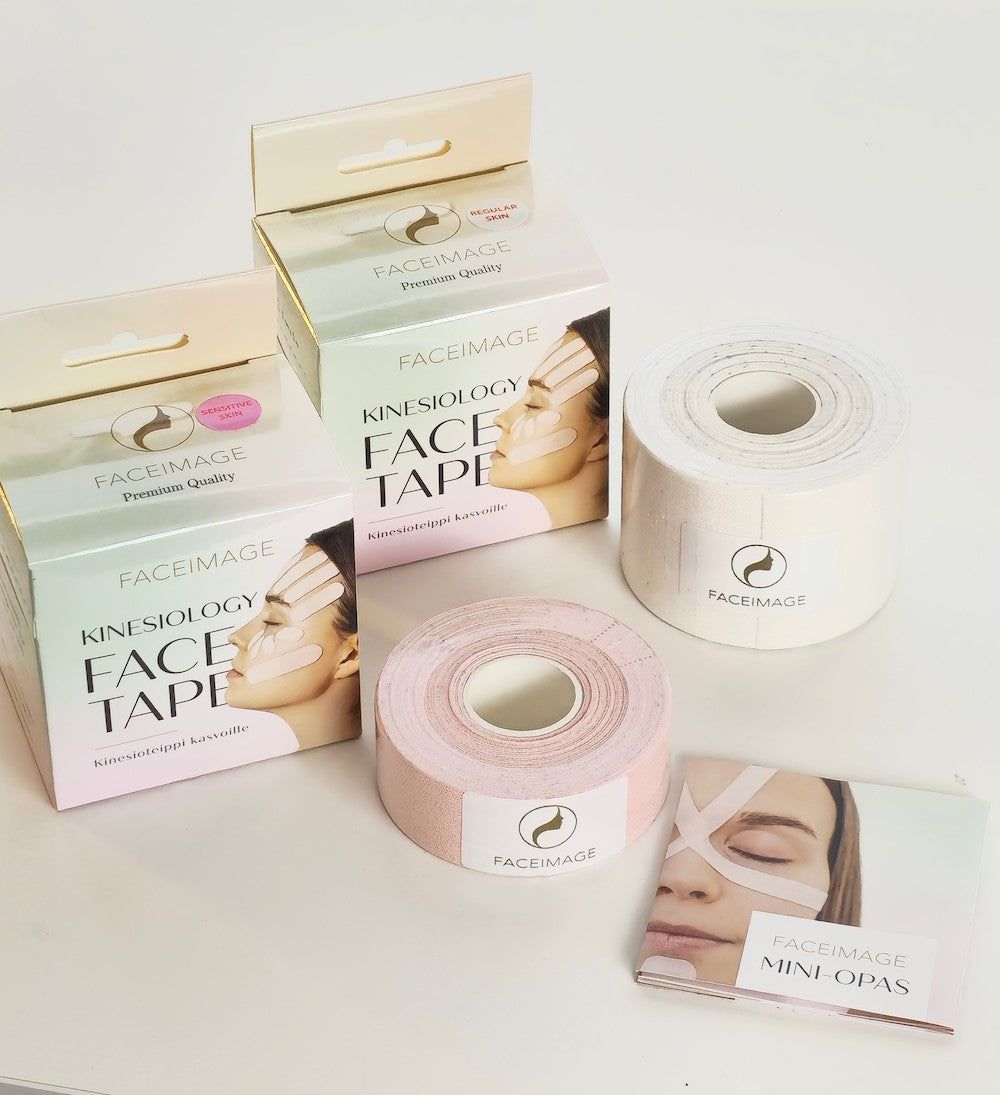 Two rolls of FACEIMAGE kinesiology face tape, one pink and one white, are displayed with their boxes and an instruction booklet featuring a woman’s face with white kinesiology tape on her cheeks and forehead. Rolls have visible perforation lines; tape has a matte finish. Packaging is rectangular with product name in bold sans-serif font. Booklet cover is mostly white; photo background is plain and light-colored.
