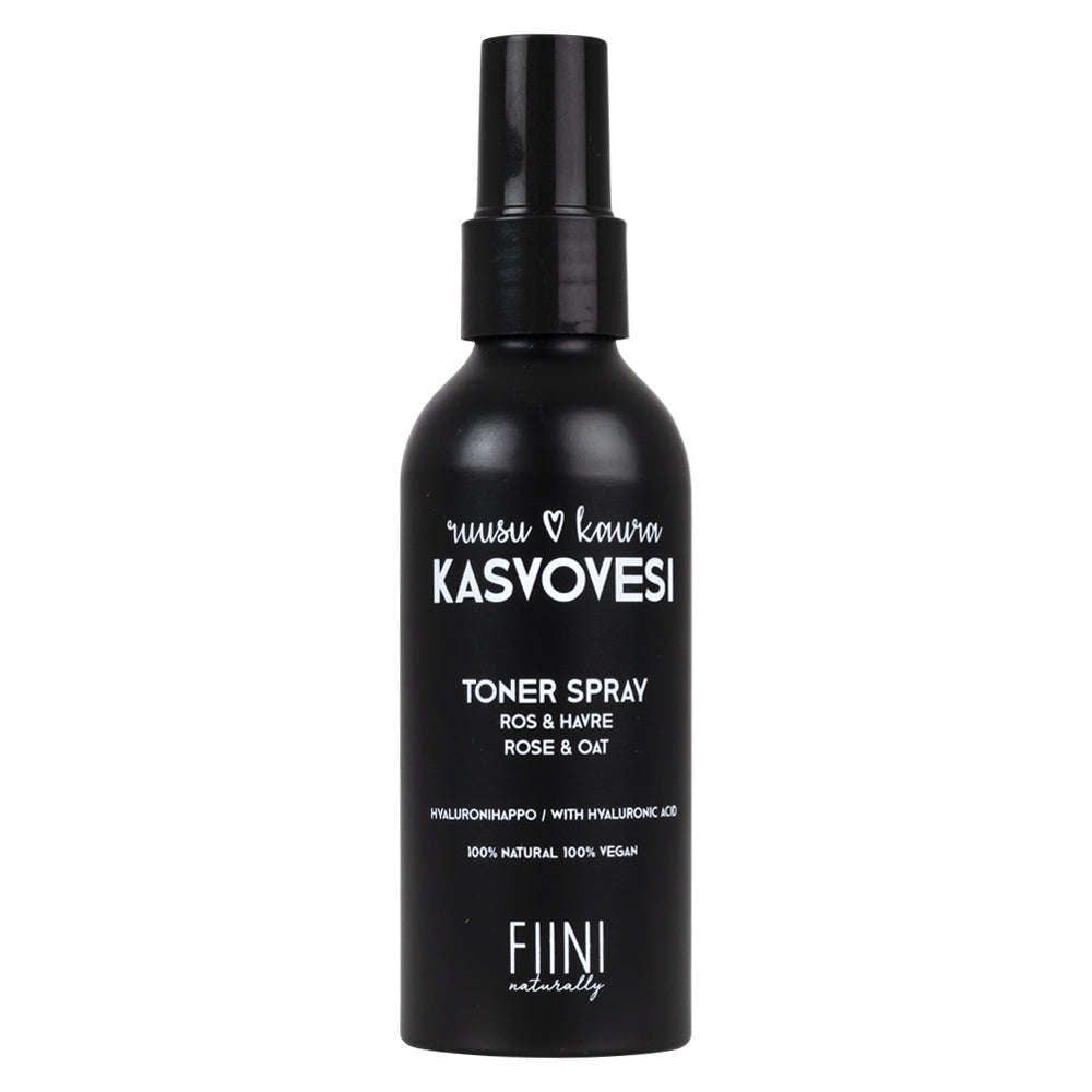 Fiini Naturally Ruusu-Kaura Kasvovesi; musta sylinterinmuotoinen pullo mattapintaisena, läpikuultava suihkusuutin päällä; etuetiketissä valkoinen groteskiteksti "Rose & Oat", "100% natural" ja "100% vegan"; minimalistinen muotoilu; ei ihmisiä tai käsiä; siisti neutraali tausta.