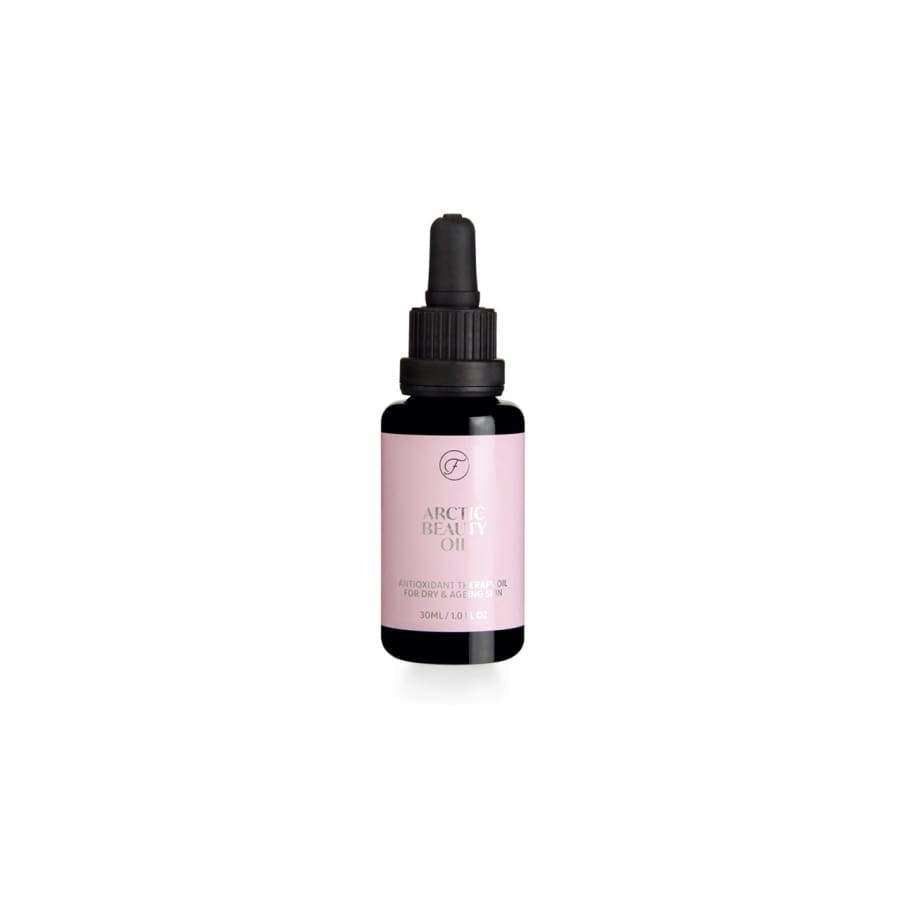 A small bottle of Arctic Beauty Oil with a pink label and a black dropper cap is placed against a white background. The bottle is cylindrical, made of clear glass with a glossy finish, and contains liquid. The pink label features the product name in bold, sans-serif typography. Packaging shows no other visible elements or accessories. No people or hands are present in the image.