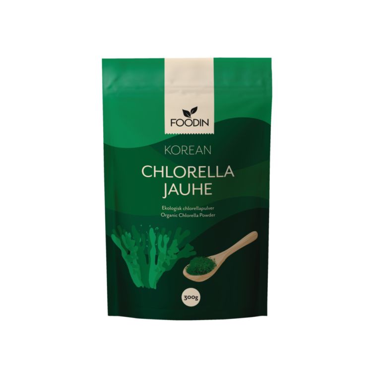 A green, rectangular, matte-finish package labeled FOODIN Korean Chlorella Jauhe is shown. The front displays an image of seaweed and a wooden spoon filled with powder. Bold white and yellow text indicates organic Korean chlorella powder, 300g. No people or hands are visible; the product is photographed against a plain background.
