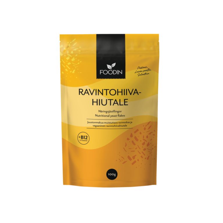 A yellow and orange 100g package of Foodin brand nutritional yeast flakes, enriched with vitamin B12, featuring text in Finnish and English and a resealable top. Matte-finish flexible pouch with vertical orientation and rounded corners. Main label uses bold sans-serif typography in white; background is plain or off-white. Product sits upright on a neutral flat surface, no people or props visible.