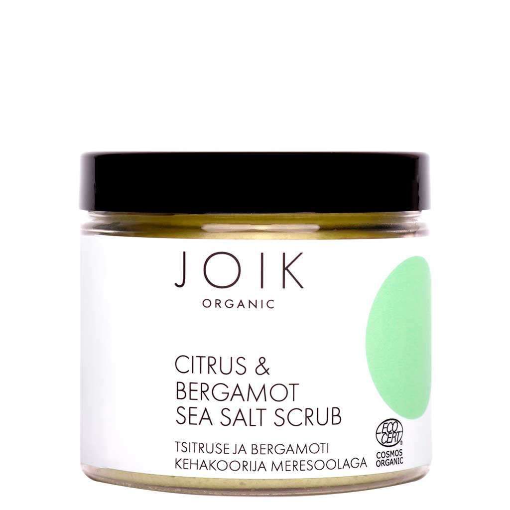 JOIK Organic Citrus & Bergamot Sea Salt Vartalokuorinta; kirkas purkki mustalla kierrekannella ja valkoisella etiketillä, vihrein elementein; kuvituksena sitrusta ja bergamottia, teksti englanniksi ja vironkielisenä; purkki sylinterinmuotoinen, sisällä karkeaa suolakuorintaa; groteskikirjasin etiketissä; neutraali studiotausta, ei ihmisiä tai käsiä.