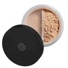 A round container of loose face powder with a black lid, partially open to reveal the finely milled light beige powder inside. The lid features a subtle, simple geometric design on top. The surface of the lid is matte with no visible typography. The container appears to be plastic with smooth sides. Background is solid white and neutral. Shot is overhead and well-lit, no people or hands present.