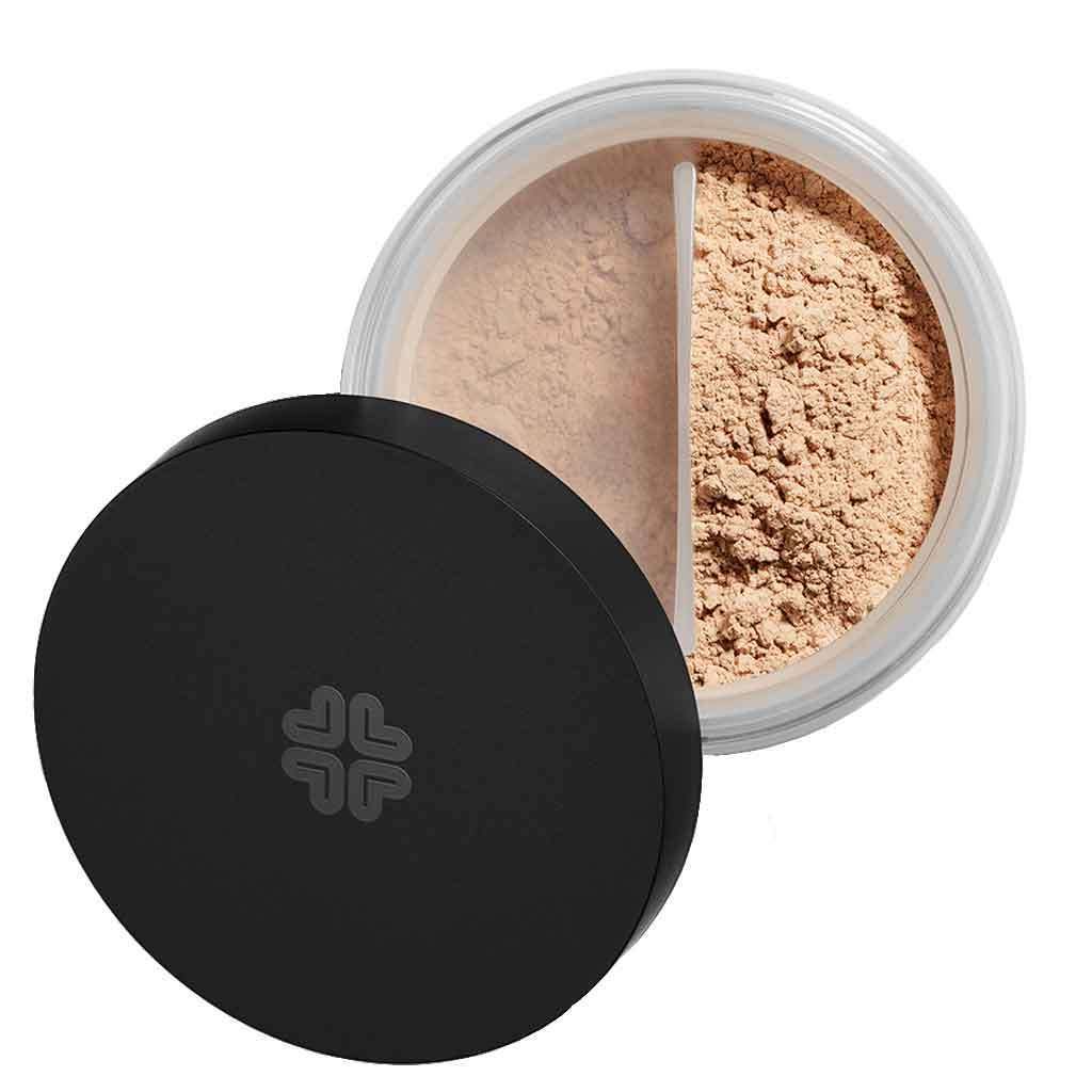 Open container of loose setting powder makeup with a black plastic lid, matte finish, resting off to the side. The jar is clear plastic and round, showing light beige powder inside. A divider or sifter is visible within the jar. No visible label text or typography on packaging. White background; no people present in the image. Studio shot, product centered in frame.