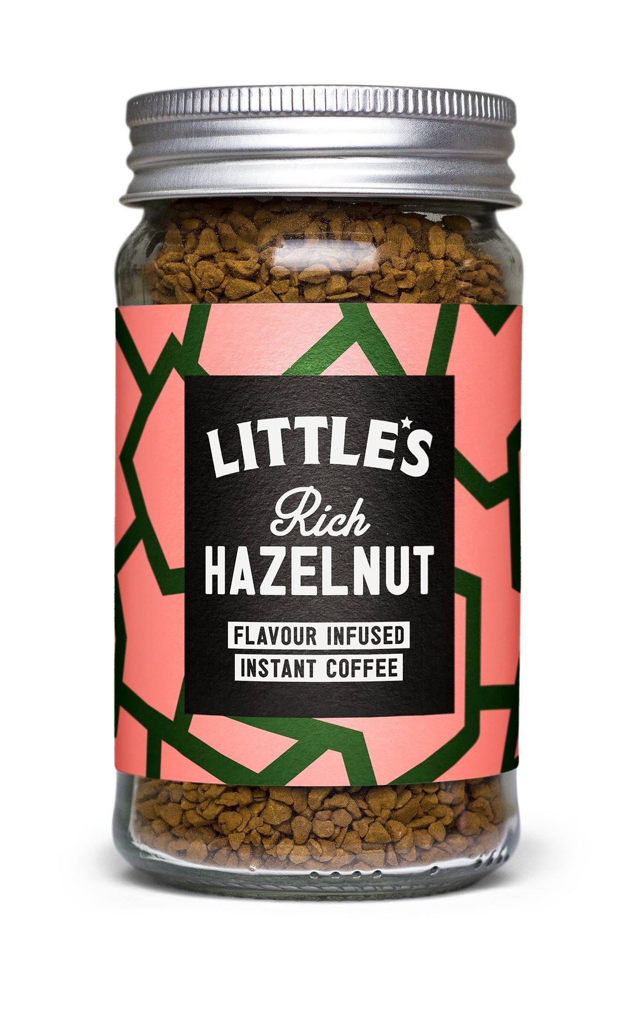 A glass jar of Littles Rich Hazelnut flavour infused instant coffee is shown. The jar has a reflective silver metal screw-on lid and a straight-sided cylindrical shape. Its front label is matte, with pink and green geometric patterns, and features legible product name text in white sans-serif font. The background is plain and well-lit; no people or hands are present in the image.
