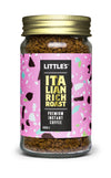 A glass jar of Littles Italian Rich Roast premium instant coffee with a round shape, transparent sides showing brown freeze-dried granules, topped with a metallic gold screw-on lid. The front label is glossy, mostly pink with multicolored accents and bold sans-serif text. Legible text includes product name and “50g.” The setting is neutral; no people or hands are present. Full product visible in the frame.