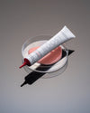 Madara BOOST Hyaluronic Collagen Hyaluronihapposeerumi; tuubi lasialustalla, vieressä vaaleanpunaista seerumia