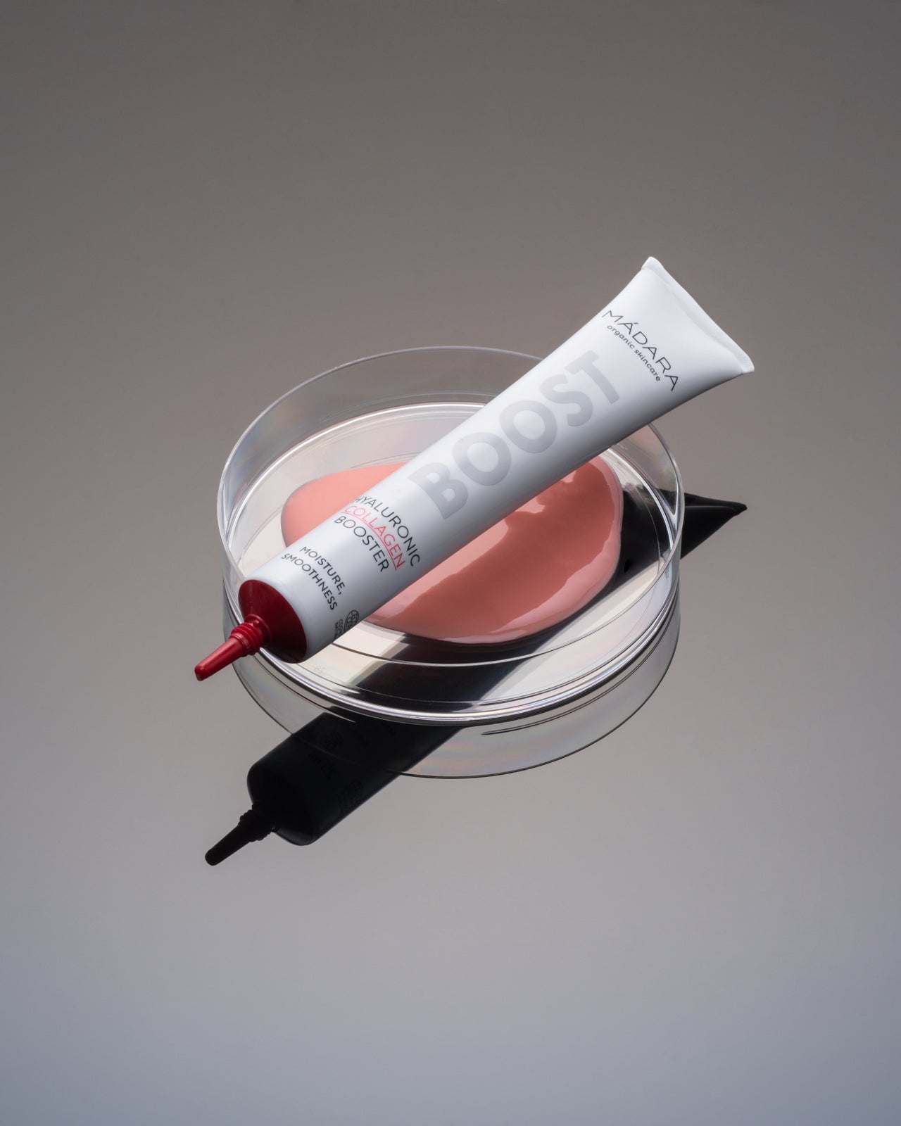 Madara BOOST Hyaluronic Collagen Hyaluronihapposeerumi; tuubi lasialustalla, vieressä vaaleanpunaista seerumia