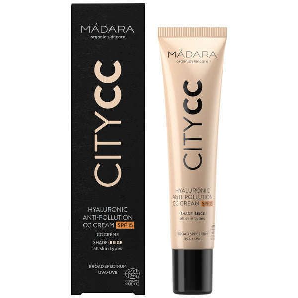 Madara City CC-voide SPF15 Beige; tuubi ja laatikko MÁDARA CITY CC Hyaluronic Anti-Pollution CC Cream -tuotetta SPF 15, sävy beige, kosteuttavalla hyaluronihapolla; suorakulmainen laatikko ja sylinterinmuotoinen tuubi, molemmat matta beigeä mustin tehostein; selkeä groteskityyppografia tuotetiedoille ja aurinkosuojatiedoille; ei ihmisiä tai käsiä kuvassa, neutraali tausta pehmeällä valaistuksella, suora edestäpäin otettu tuotekuva.