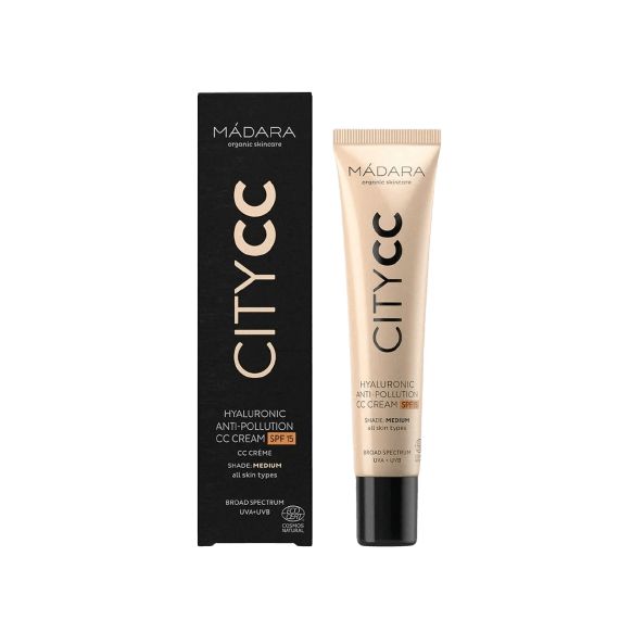 Madara City CC-voide SPF15 Medium -tuubi mustan ja kultaisen laatikkopakkauksen vieressä, molemmat pystyssä valkoisella taustalla; tuubi sylinterimäinen mattapinnalla, laatikossa kiiltävän mustia ja metallisen kultaisia osioita; molemmissa tekstausvapaata typografiaa valkoisella tai kultaisella; ei ihmisiä tai käsiä näkyvissä.