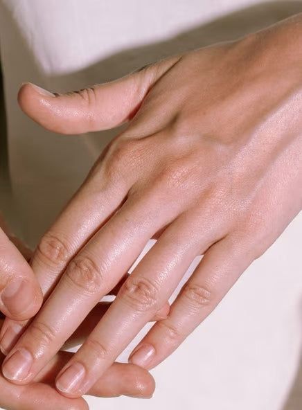 Madara Deep Comfort käsivoide; lähikuva henkilön käsistä puhtain, luonnollisin kynsin lepäämässä toistensa päällä vaalealla taustalla, hoidetut sormenpäät; kynnet lyhyet ja sileät ilman lakkaa; ei näkyviä esineitä tai pakkausta.