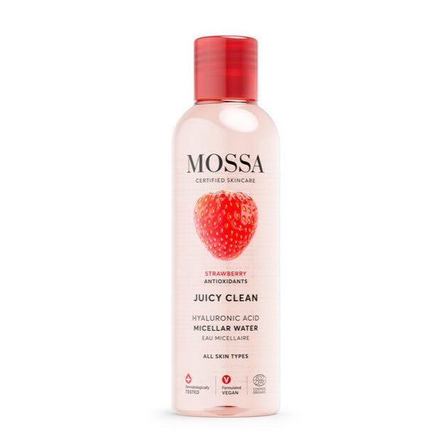 Mossa Juicy Clean Misellivesi; kirkas, lieriön muotoinen muovipullo kiiltävällä punaisella kierrekorkilla; valkoinen etiketti mustaa ja punaista groteskitekstiä sekä mansikkakuva edessä; sisältää hyaluronihappoa ja antioksidantteja; vaalea tausta.
