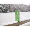 Vihreä Natural Energy Drink -tölkki lumisella puukaiteella talvimaisemassa