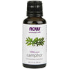 NOW Essential Oils 100% Pure Camphor (Cinnamomum camphora), 1 fl. oz. (30 mL); ruskea, lieriömäinen, kiiltäväpintainen pullo; etiketissä kuva vihreistä lehdistä sekä selkeää groteskitekstiä valkoisella pohjalla; tekstissä mainitaan tilavuus ja "pure oil"; vaalea tausta, ei ihmisiä.