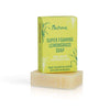 Nurme Sitruunaruoho -palasaippua, "Super Foaming Lemongrass Soap"; keltavihreä pystyssä oleva rasia beigen suorakulmaisen saippuapalan päällä; pakkaus mattapintainen, painettuja sitruunaruohokuvituksia; teksti mainitsee kookoksen ja villin sitruunaruohon; lihavoitua groteskitekstiä tuotenimelle; vaalea tausta, ei ihmisiä tai toimintaa; kuvattu edestäpäin.