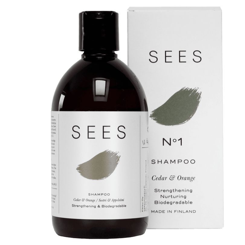 SEES biohajoava shampoo seetri & appelsiini; lieriön muotoinen, mattapintainen ja valkoinen pullo mustalla kierrekorkilla, vierellä sitä vastaava suorakulmainen mattapintainen valkoinen pakkaus mustin tekstein; groteskiteksti "No1", "Cedar & Orange" sekä maininnat biohajoavuudesta, vahvistavuudesta, hoitavuudesta ja Suomessa valmistamisesta; vaalea tausta.