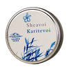 A round metal tin is shown with a matte silver finish, labeled “Sheavoi Karitevoi” in bold sans-serif lettering. The lid displays blue plant illustrations and the logo “Saaren Taika.” The tin sits on a plain white background. No people or props are present, and the image is a close-up product shot taken from above.