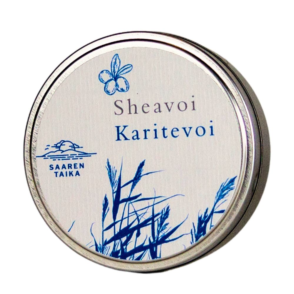A round metal tin is shown with a matte silver finish, labeled “Sheavoi Karitevoi” in bold sans-serif lettering. The lid displays blue plant illustrations and the logo “Saaren Taika.” The tin sits on a plain white background. No people or props are present, and the image is a close-up product shot taken from above.