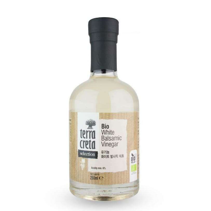 Terra Creta Luomu Balsamiviinietikka -pullo, 250 ml; kirkas, sylinterimäinen lasipullo mustalla kierrekorkilla, sisällä läpinäkyvää nestettä; mattapintaisessa beigessä paperietiketissä englannin- ja koreankielistä tekstiä sekä luomusertifiointimerkkejä; kuvattu pystyssä yksiväristä taustaa vasten, ei ihmisiä tai muita esineitä.